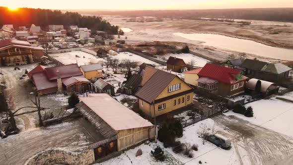 Outskirts of the Village Under the Snow in the Orange Light of the Sun