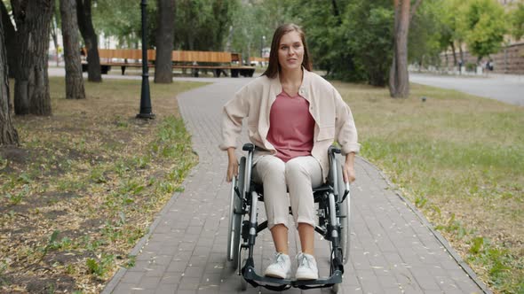 Slow Motion of Cheerful Paraplegic Girl Riding Wheelchair and Smiling in Autumn Park