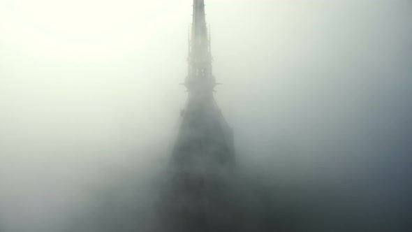 Drone Rising Above Foggy Clouds To Reveal Epic Golden Statue on Top of Iconic Mont Saint Michel