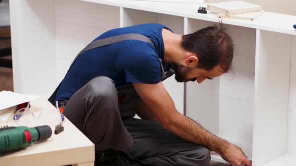 Male Worker Using a Screwdriver for Furniture Assembly