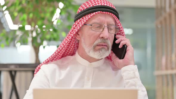 Old Arab Businessman with Laptop Angry on Smartphone