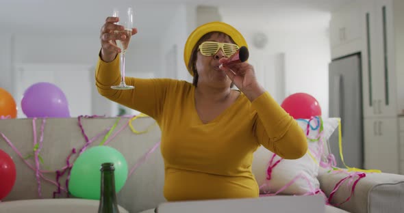 Happy african american senior woman raising champagne glass making new year's eve laptop video call