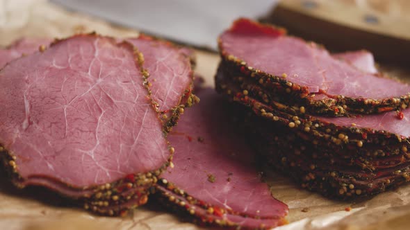 Delicious Peppered Roast Beef Pastrami Slices on Paper with Grains of Coloured Pepper