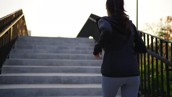 4K Asian woman running up stairs while jogging at public park in the morning.