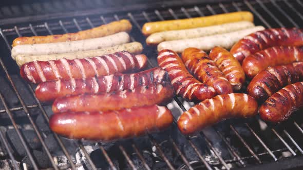 Brats Being Cooked on a Grill with Flame and Smoke