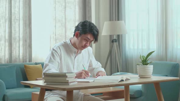 Asian Man Student Writing In Notebook On The Table While Studying At Home