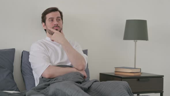 Young Man Thinking While Sitting in Bed