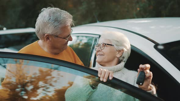 Senior Couple Purchased New Car. Standing Near the Door and Woman Waving with Keys