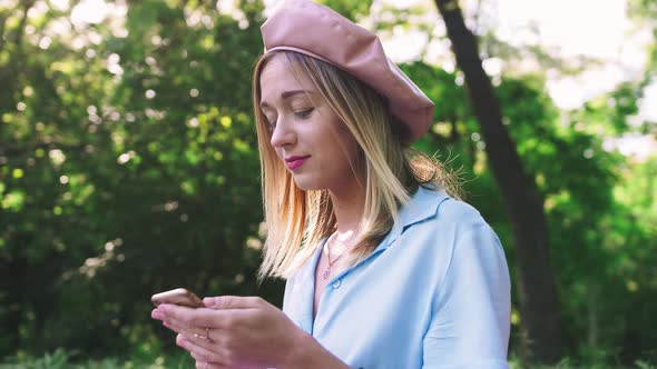 Young Stylish Woman Using Her Cell Phone Outdoor in the Park on Picnic Close Up