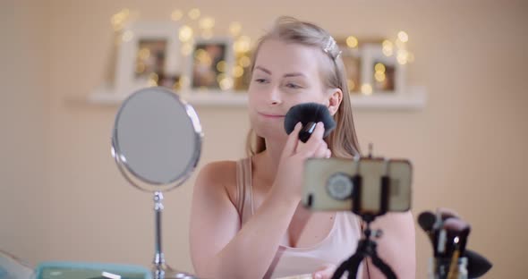 Young Woman Doing Makeup in Front of Mirror at Home