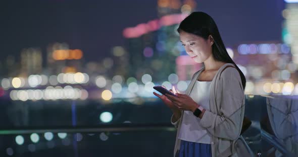 Woman use of mobile phone online in city at night