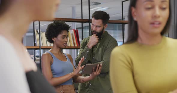 Diverse male and female business colleagues talking and using tablet