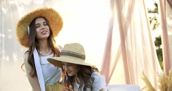 Two Cheerful Brunette Girls with Long Hair in Straw Hat Smiling and Posing to the Camera