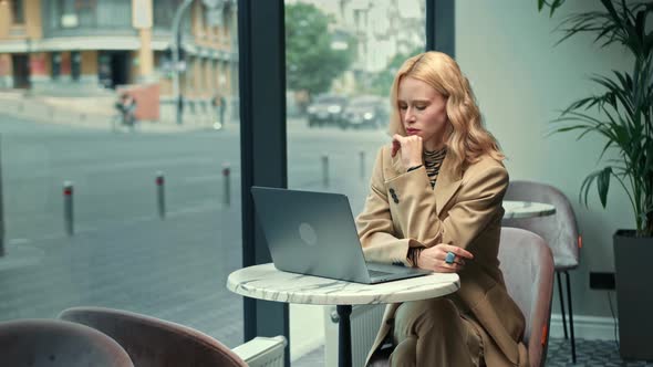 A beautiful woman is upset, she is on a zoom call in a cafe with her boss. Freelancer, businessman.