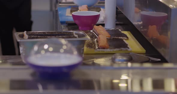 Cooking Delicious Sushi on Table Near Plates on Conveyor