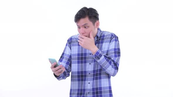 Happy Young Asian Hipster Man Using Phone and Looking Surprised