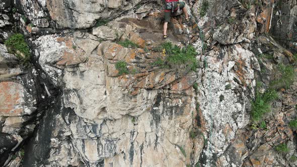 Man Athlette Climbing on the High Rock in the Mountains