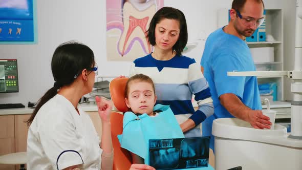 Pediatric Dentist Showing Dental Problems Holding Radiography