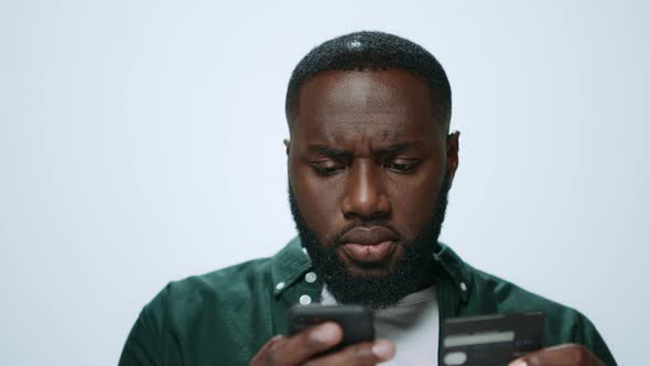 Focused African Man Successfully Shopping Online on Smartphone in Studio