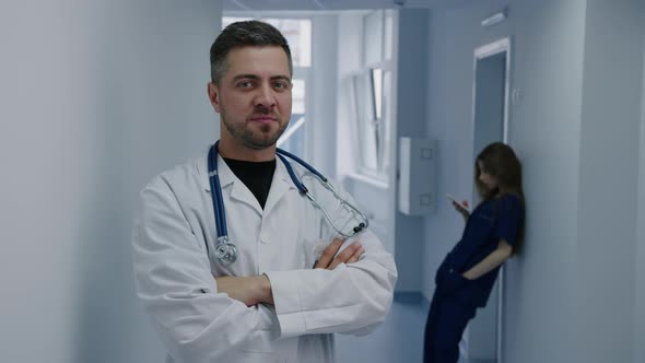 A Successful Male Doctor Smiles and Looks at the Camera Standing in the Corridor of the Hospital