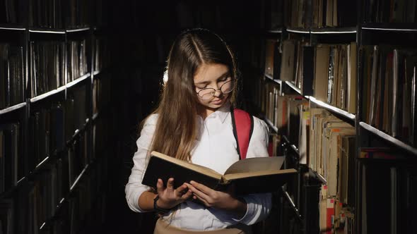 Girl with Glasses Reading a Book in the Library