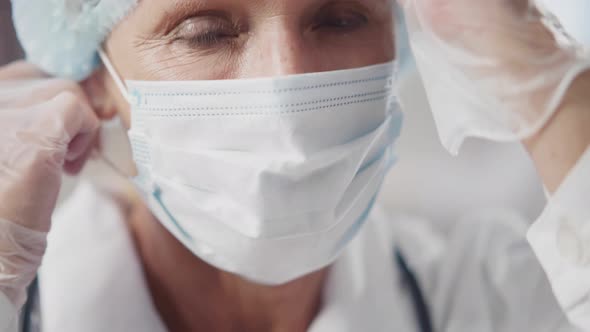 Close Up of Mature Doctor Remove Safety Mask and Cap Smiling at Camera