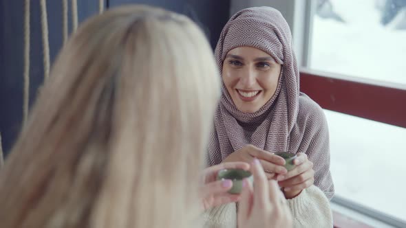 Joyful Arabic Woman Is Listening Story of Her Blonde Friend Woman in Cafe