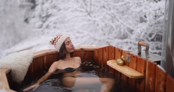 Woman Relaxing in Hot Bath at Snowy Mountains