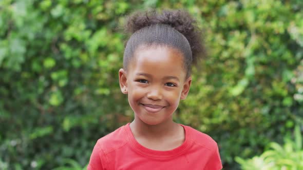Animation of happy african american girl looking at camera in garden