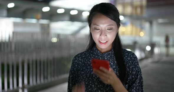 Woman search on cellphone in city at night