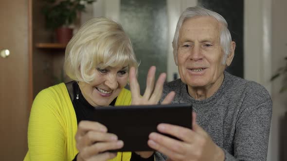 Pretty Mature Senior Couple Grandparents Enjoy Online Shopping on Tablet at Home