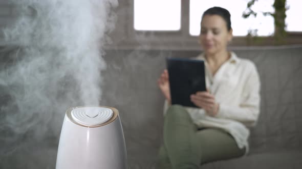 Woman with humidifier into dry air room. 