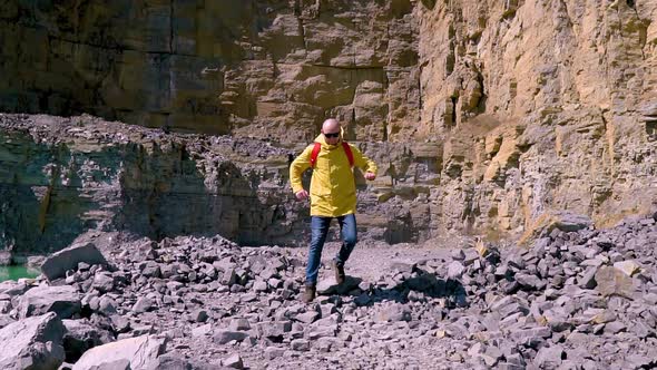 Mountain Hiker. Man Run in the Mountains in a Yellow Raincoat and a Red Backpack. Sport Orienteering