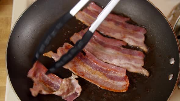 Cooking Bacon Being Flipped in a Pan