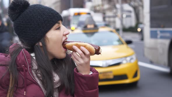 Young Woman Eats a Hot Dog in the Streets of New York