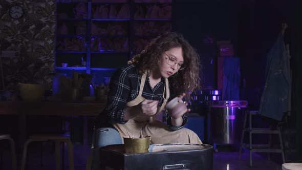 Woman with Curly Hair Wiping Out the Surface of the Fresh New Pot Made Out of Clay