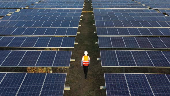 Aerial drone view technician walking between solar panels row