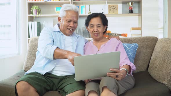 Happy Asian senior couple uses the laptop to find vacation destinations in the holiday season