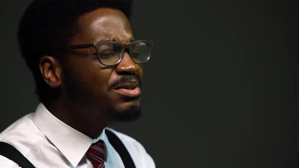 Handsome African American Man in a Stylish Suit and Glasses Sings with Pleasure Closing His Eyes