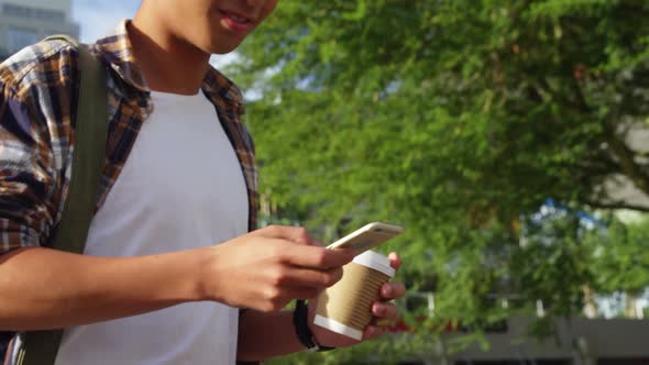 A man texting on his smartphone and holding coffee