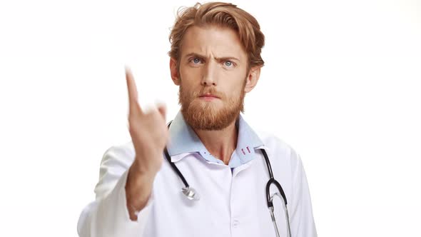 Serious Male Caucasian Doctor Scolding and Waving Hand at Camera on White Background