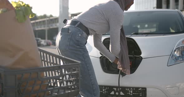 Black Muslim Girl Charging Electro Car at the Station