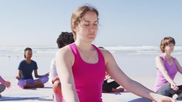 Multi-ethnic group of women doing yoga position on the beach and blue sky background