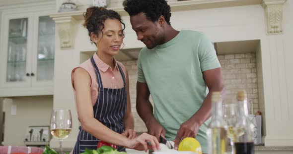 Happy biracial couple cooking together, cutting vegetables