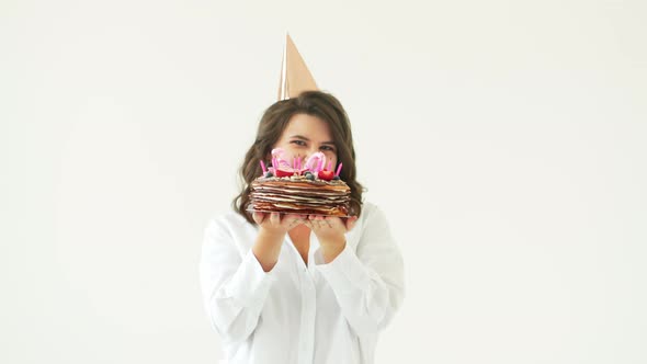 a Happy Woman Dancing with a Birthday Cake with Candles on a White Background