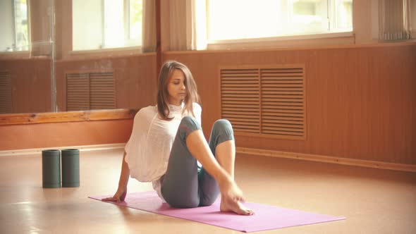 Young Woman Gymnast Warming Up on the Floor and Doing Exercises on Her Legs