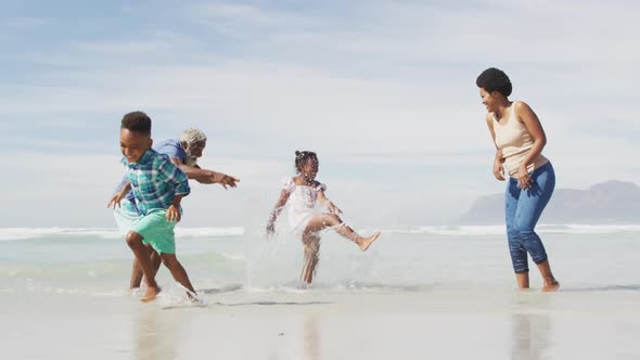 Happy african american couple playing with children on sunny beach