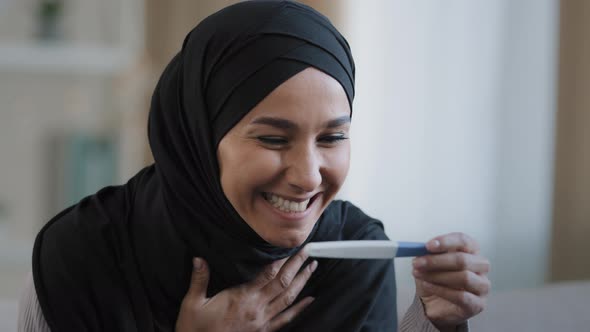 Joyful Islamic Young Woman in Hijab Smiling Happily Holding Pregnancy Test Excited Pregnant Lady