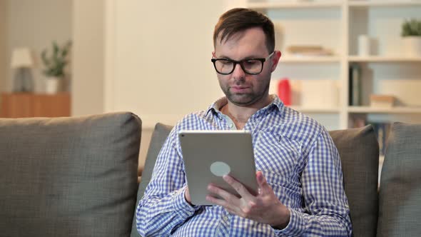 Young Man Celebrating Success on Tablet at Home 