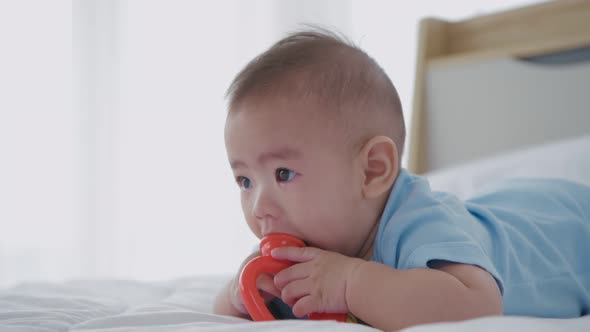 Family concept. The baby is lying alone playing with toys on the bed. 4k Resolution.